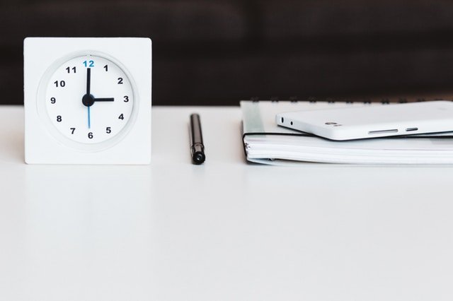 Bild von einer Uhr einem Stift und einem Heft. Werkzeuge, zum Prokrastination überwinden