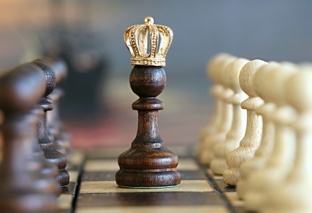 Bild von Schachfiguren auf einem Schachbrett, von denen eine eine Krone trägt, was markiert, welche Lernstrategie die beste ist